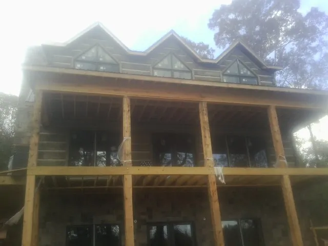 Dormers and porch framing on a large log home under construction — Roof Coating work by our crew in Breaux Bridge
