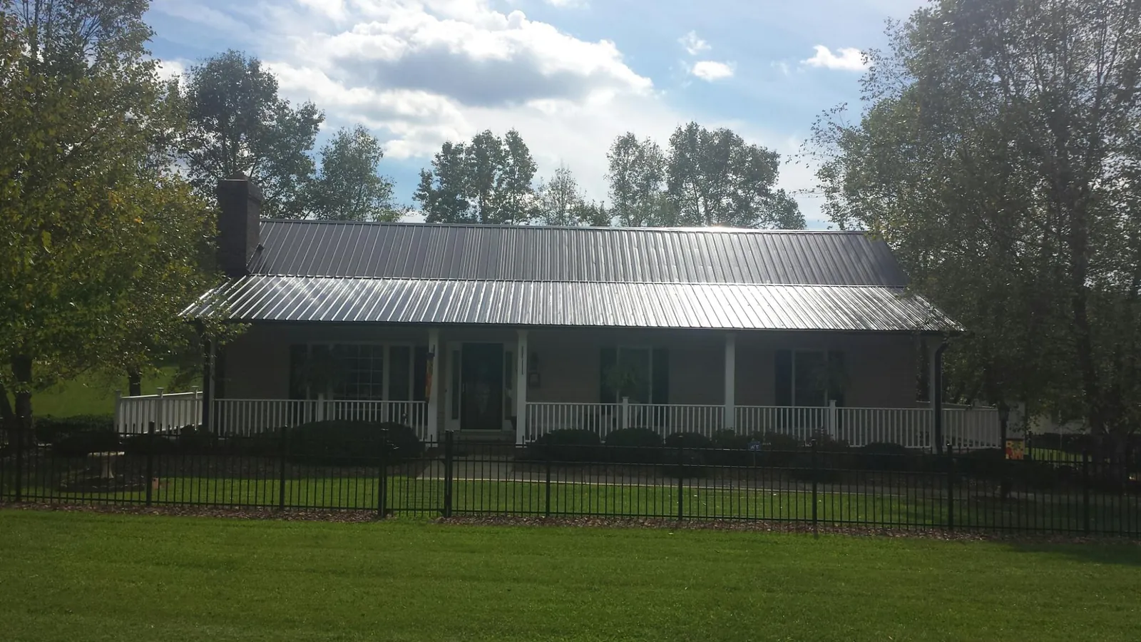 Gray metal roof on a brick ranch with a full width front porch — Gutter Guard Installation work by our crew in Breaux Bridge